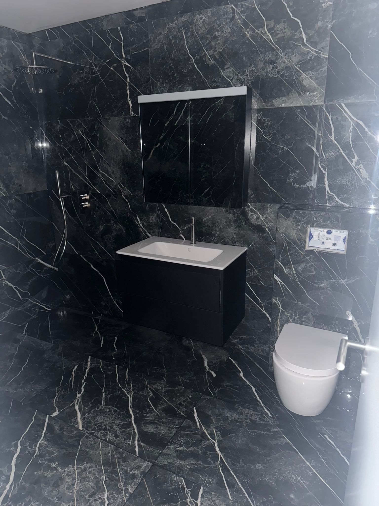 Apres renovation par BNG Renovation : salle de bain en marbre noir a Corseaux, douche italienne et vasque design