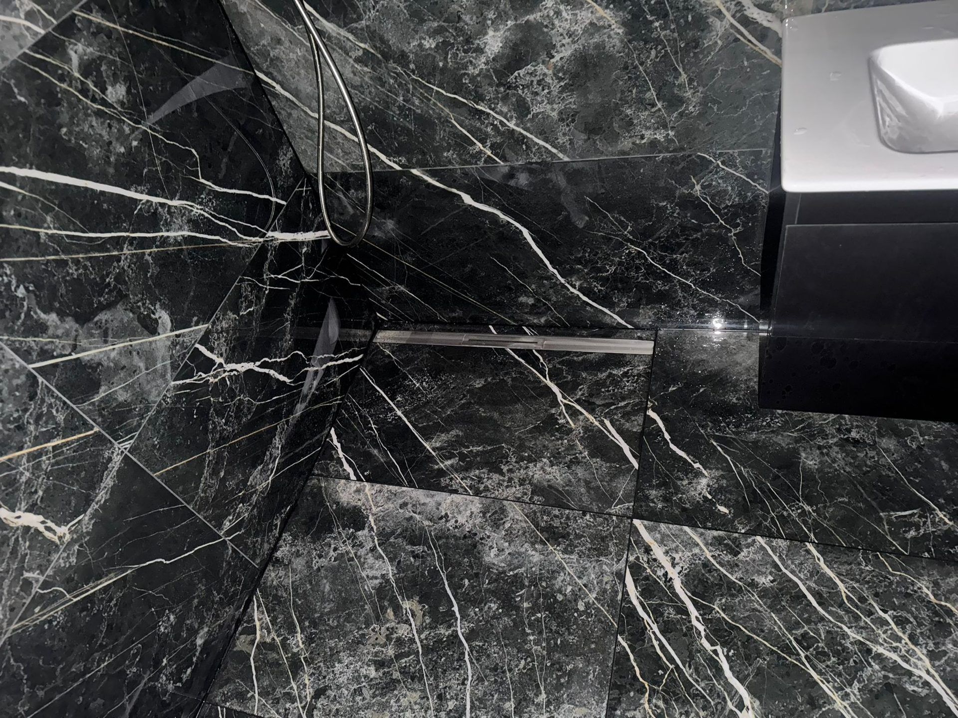 Salle de bain en marbre noir dans une villa a Corseaux par BNG Renovation : douche italienne et vasque sur mesure